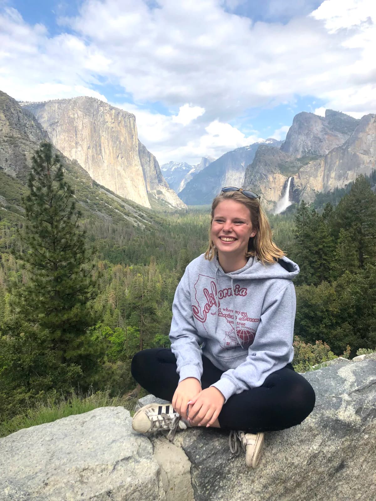 Une étudiante souriante devant une vue spectaculaire du parc national de Yosemite, une expérience inoubliable lors de l'année scolaire aux États-Unis.