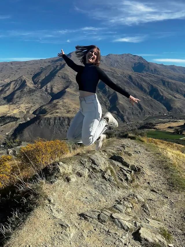 Étudiante sautant dans un paysage naturel pendant une année scolaire en Nouvelle-Zélande, illustrant liberté, découverte et immersion.