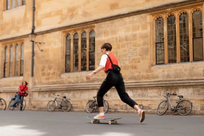 Étudiant se déplaçant en skateboard devant un bâtiment scolaire anglais, illustrant la vie quotidienne pendant une année scolaire en Angleterre.